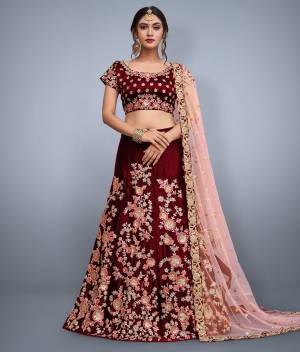 This set features a maroon velvet blouse with golden sequin and floral embroidery on the front and back. It is paired with maroon flared velvet lehenga skirt machine embroidered with gold floral sequin and peach thread work all over the ghera. The lehenga set comes along with Pastel Pink soft net dupatta ornated with over butti and rich embroidered border on all four sides.