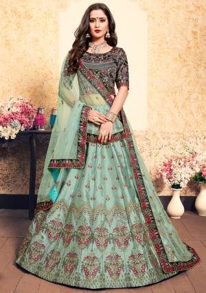 This Wedding Season, Be The Most Attractive Wearing This Heavy Designer Lehenga Choli In Dark Green Colored Blouse Paired With Contrasting Mint Green Colored Lehenga And Dupatta. Its Blouse And Lehenga Are Satin Based Paired With Net Fabricated Dupatta. 