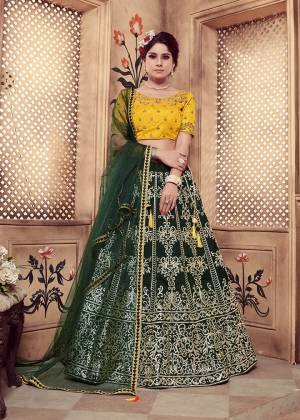 Add This Very Beautiful And Attractive Looking Heavy Designer Lehenga Choli In Yellow Colored Blouse Paired With Contrasting Dark Green Colored Lehenga And Dupatta. Its Blouse And Lehenga Are Art Silk Based Paired With Net Fabricated Dupatta. 