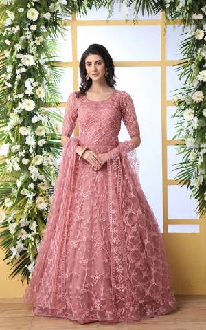 Look Pretty In This Designer Floor Length Gown In Pink Color Paired With Peach Colored Dupatta. Its Heavy Embroidered Top Is Fabricated On Net Paired With Net fabricated Dupatta. Buy This Semi-Stitched Designer Gown Now.