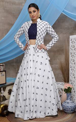 Here Is A Rich And Elegant Looking Lehenga Choli Which Comes With A Jacket. Its Attractive Blouse Is In Navy Blue Color Paired With White Colored Lehenga And Jacket. This Whole Pair Of Lehenga, Choli And Jacket Are Cotton Based, Beautified With Pretty Work. 