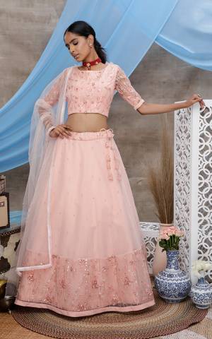 Look Pretty In Light Peach Colored Designer Lehenga Choli. This Pretty Piece Is Net Based Beautified With Elegant Tone To Tone Embroidery. 